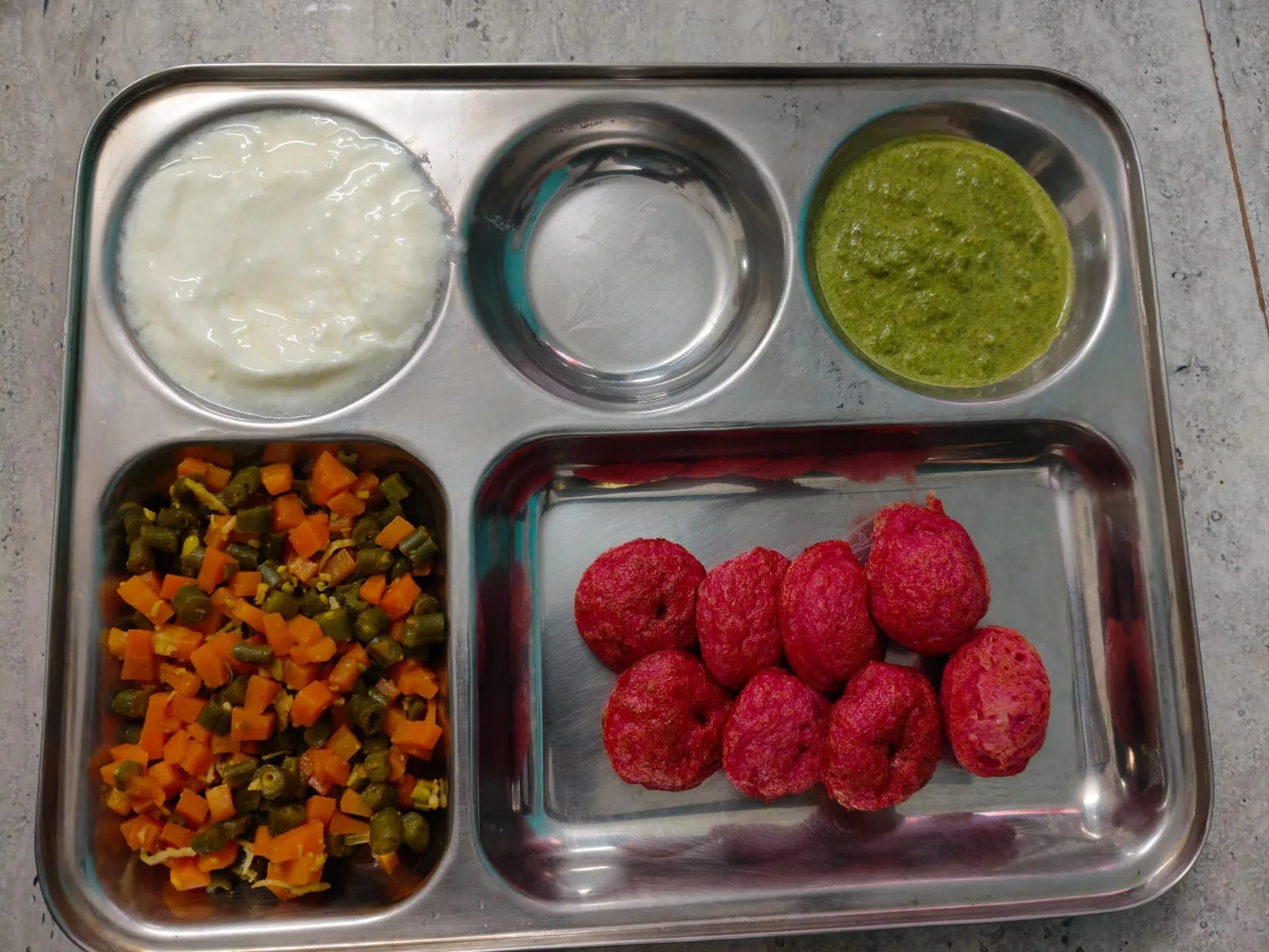 A meal plate with idli, sautéed mixed vegetables (carrots and beans), curd, and green chutney, a gut-friendly meal pattern adjusted for her ulcer and gastritis history