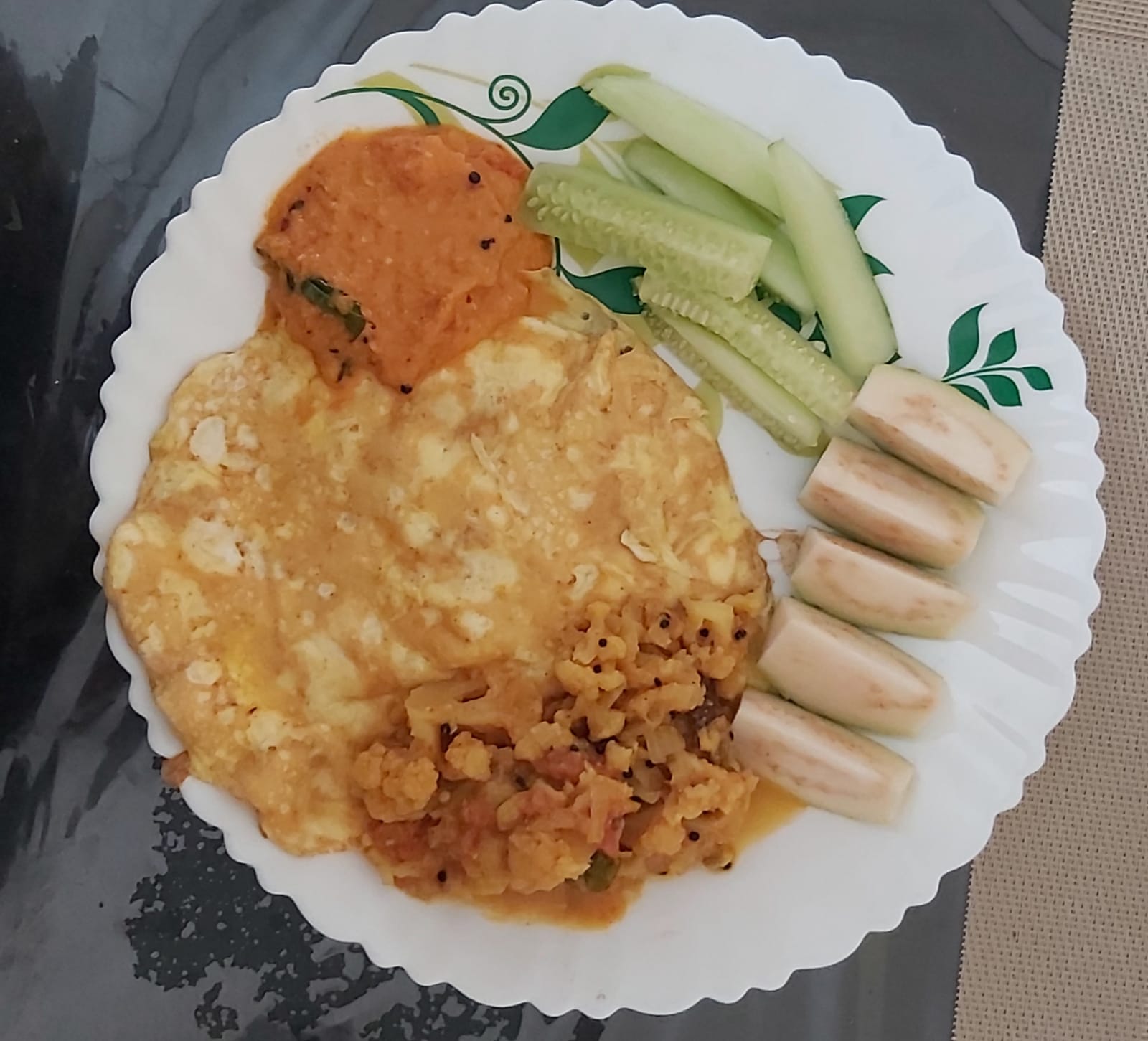 Another structured meal plate, with an omelette, cauliflower poriyal, chutney, banana and cucumber