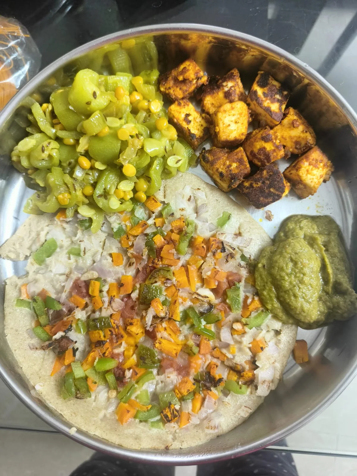A vegetable-topped millet uttapam with green chutney, pan-roasted paneer cubes, and a ridge gourd stir-fry with dal