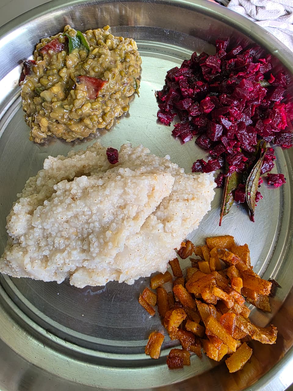 A home meal from Arthi's plan: millet, green moong dal curry, beetroot poriyal and a vegetable stir-fry on a steel plate