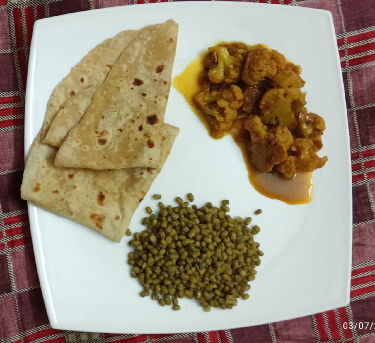 A plate of two chapatis with cauliflower curry and a portion of sprouted green gram