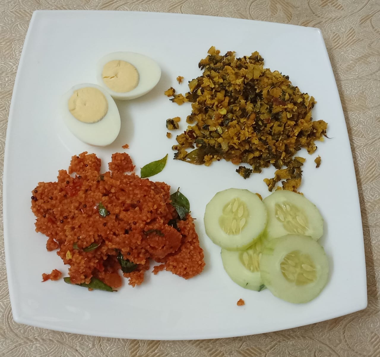 A plate of a boiled egg, a greens poriyal, tomato millet, and cucumber slices