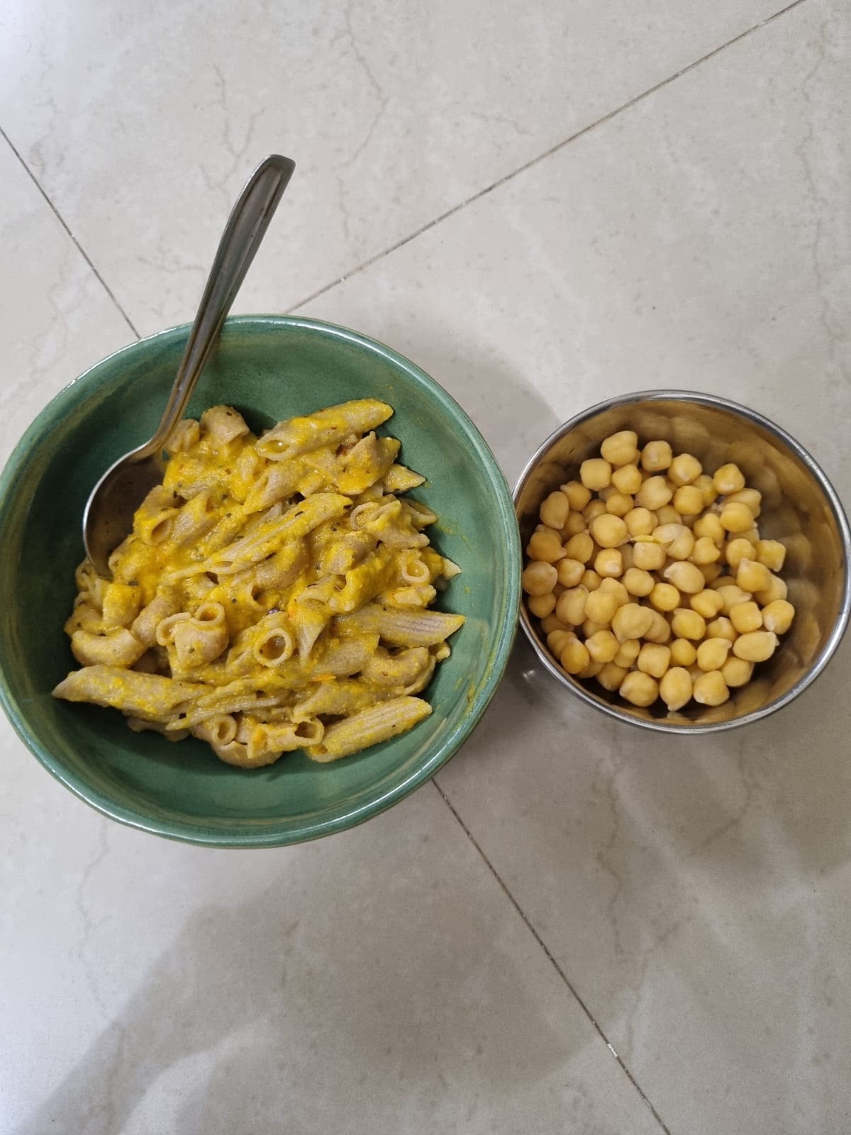 A bowl of wholewheat penne in a light vegetable sauce with a bowl of boiled chickpeas