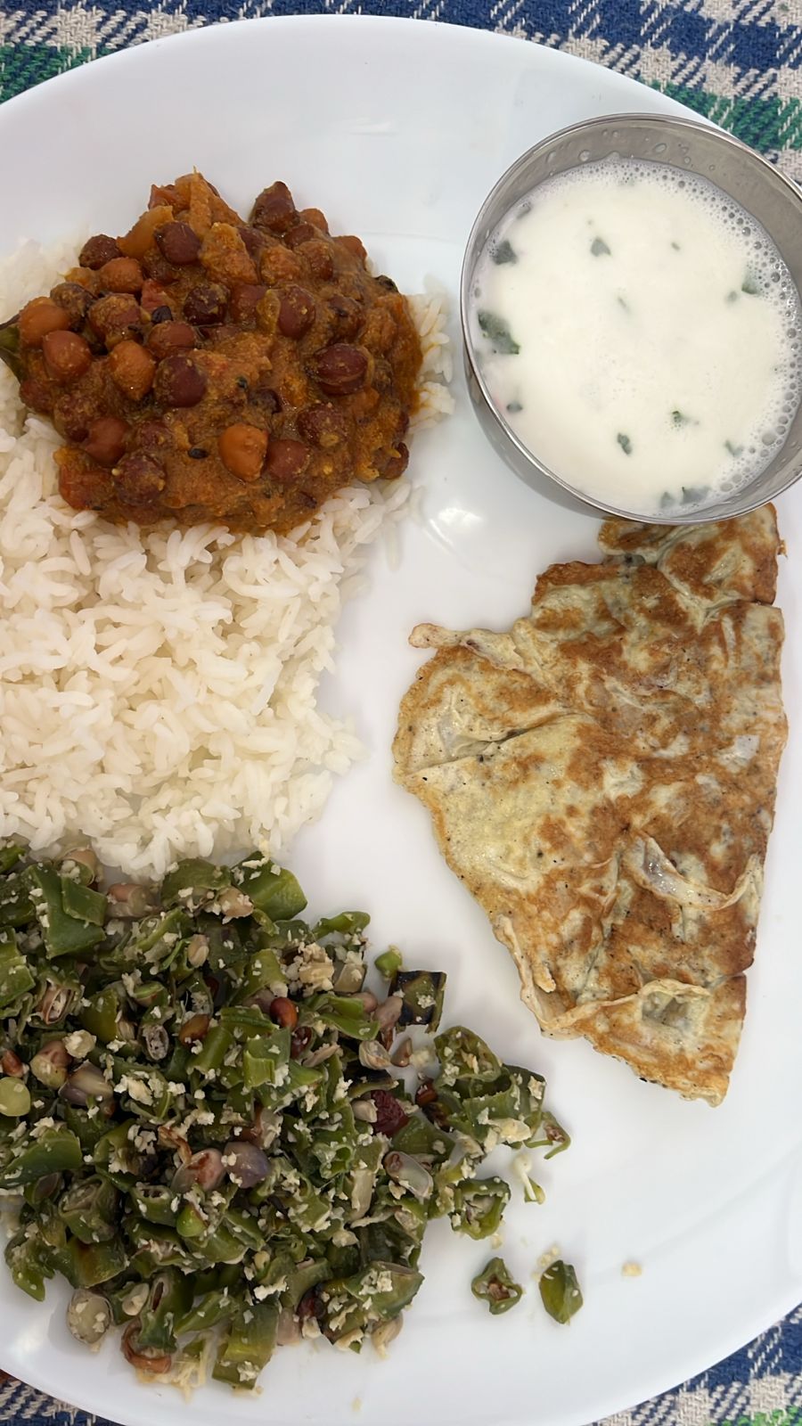 A complete lunch: rice with chana curry, green beans poriyal, egg omelette, and buttermilk
