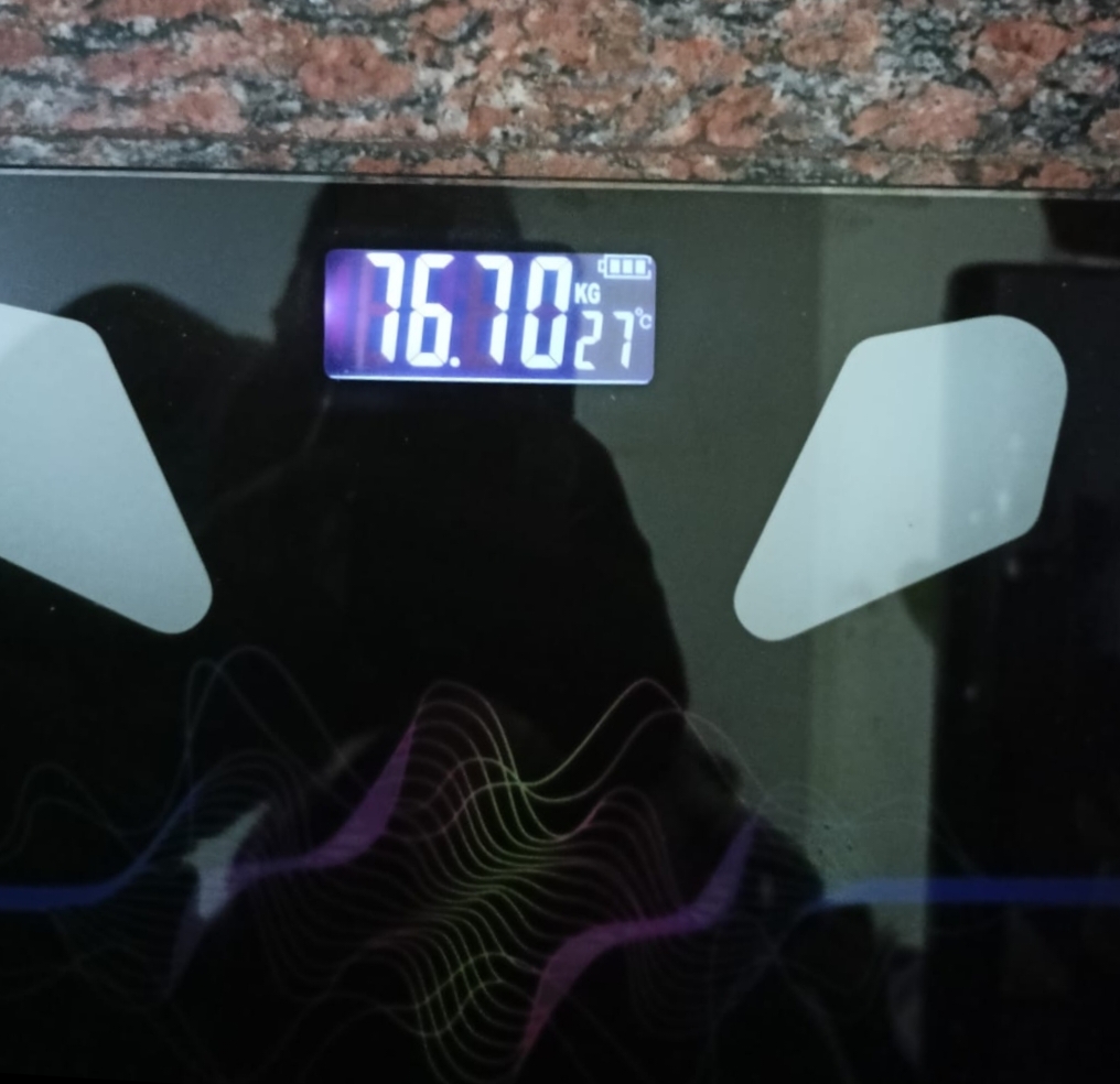 Scale showing Madhu's weight at 76.70 kg after the program