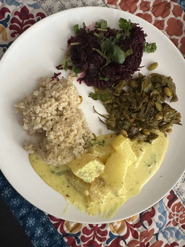 A colourful plate with cooked grains, a beetroot salad, a green vegetable curry and a light kurma