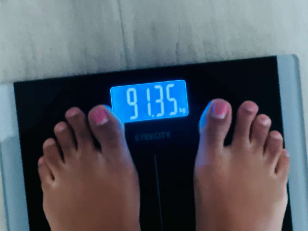 A digital bathroom scale reading 91.3 kg, the starting weight recorded at the beginning of the program