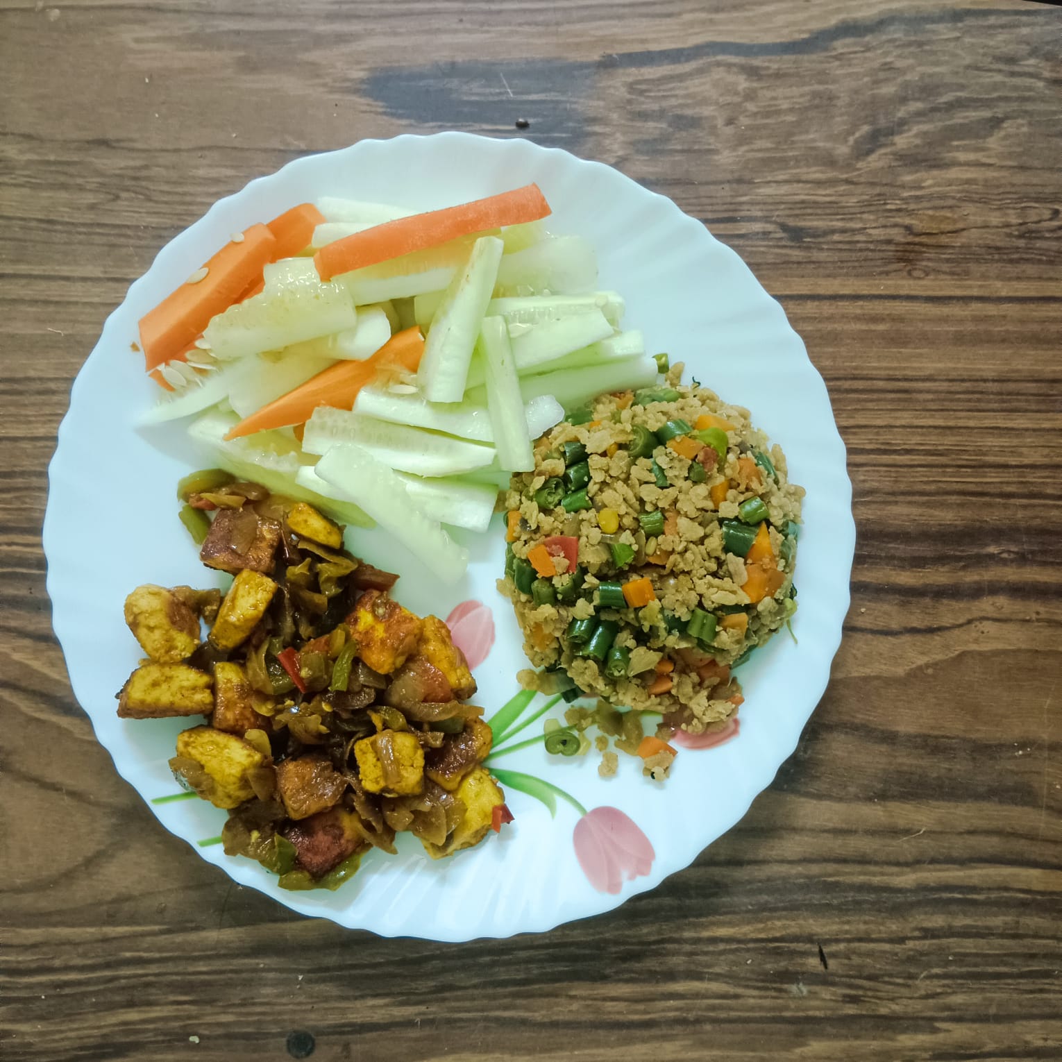 A balanced plate with paneer and vegetable stir-fry, a soya and vegetable portion, and fresh cucumber and carrot sticks