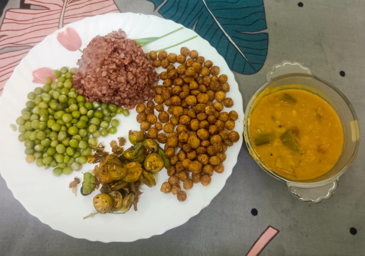 A home-cooked plate with a mixed vegetable and lentil dish, greens and a portion of grains